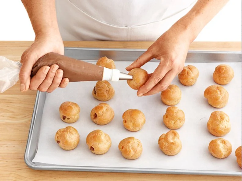 Small Round Pastries Being Injected with Chocolate