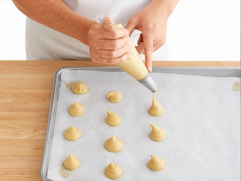 Dough for Pastry Puffs being Poured from Pastry Bags onto Wax Paper