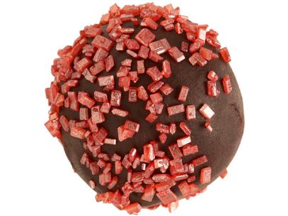 A Rum Ball covered in red translucent sprinkles placed against a white background