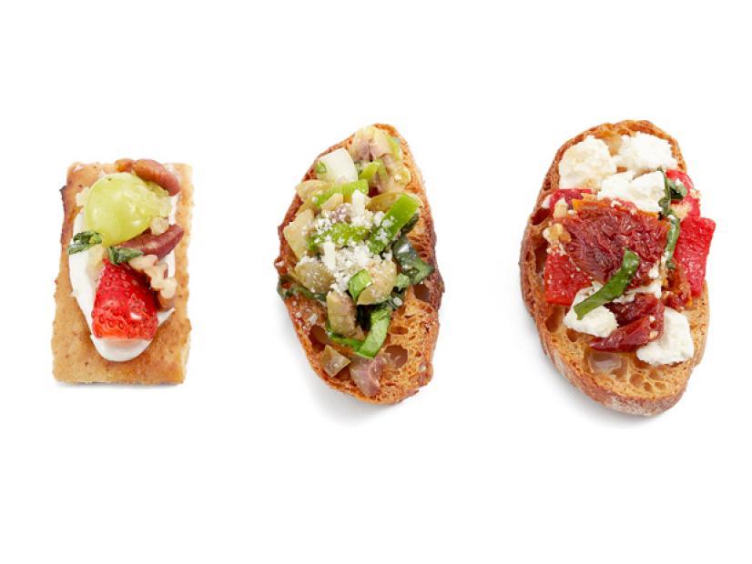 Bruschetta topped with a variety of cheese, fruit and vegetables