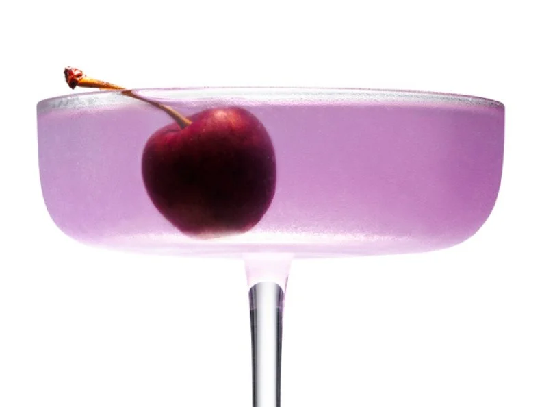 A light Purple Cocktail with a Cherry in it