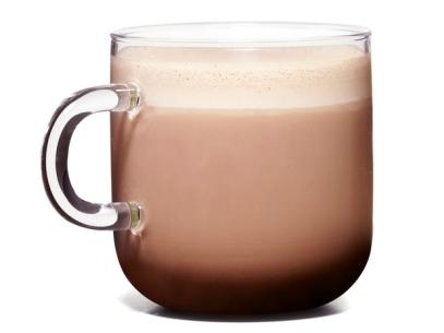 A Glass Mug Full of Frothy Cocoa Against a White Background