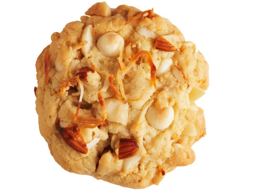 A cookie made with white chocolate chips, almonds and macadamia nuts placed against a white background