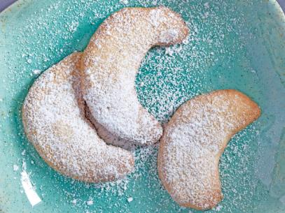 Mexican Wedding Cookies with powder sugar on a grainy blue dish