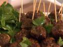 Several Curry Scallion Meatballs piled on a dish with wooden picks sticking out of many of them