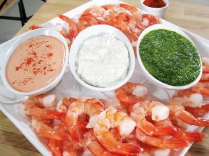 A Variety of Shrimp Cocktail Aligned in a row on a tray full of shrimp