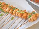 Skewered Chicken aligned in a row on a plain white plate