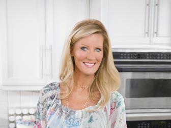 Sandra Lee holding green leafy ingredients in a glass dish in one hand and canned ingredients in another 