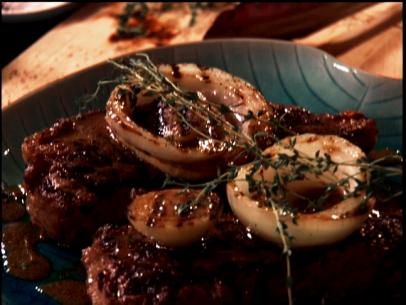 Two steaks grilled with sauce and vadalia onions and topped with thyme