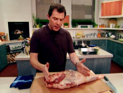 Bobby Flay measuring out a portion of raw Leg of Lamb with his hands