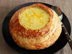 Soup in a bread bowl topped with various shredds of cheese