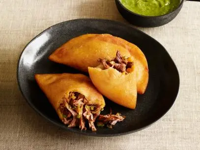 Two empanadas on a small black plate
