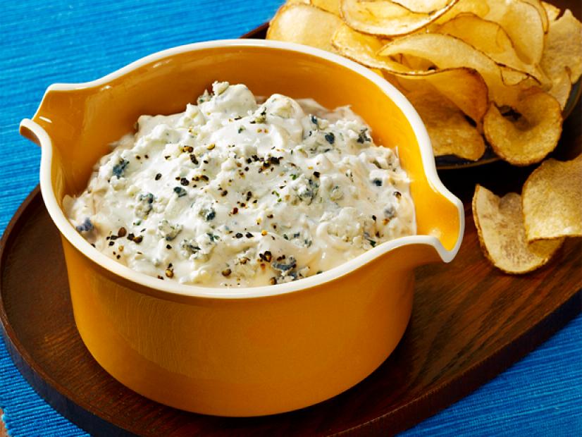 Chunky dip in a yellow dish on a plate alongside plain potato chips