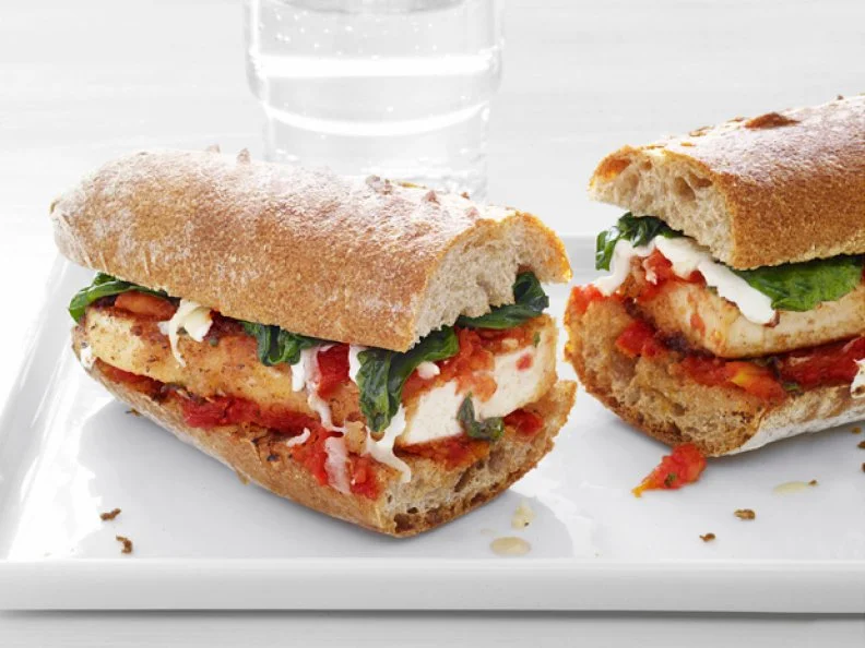 Tofu and Parmesan Sandwich sliced in half on a white tray