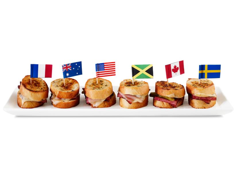 Six Sandwiches aligned in a roll with miniature flags from various countries sticking out of them