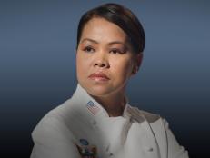 Headshot of Cristeta Comerfor wearing a white chefs uniform against a blue backdrop