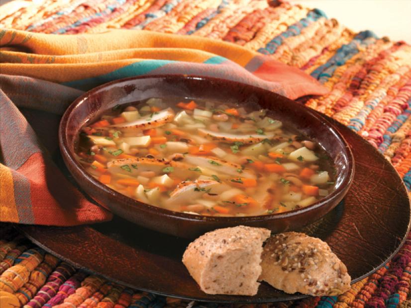 Chicken and Vegetable soup in a brown bowl placed on a mult-colored place mat