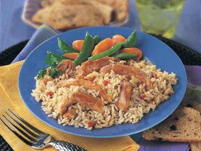 Rice with slices of chicken on a blue plate next to green beans and carrots