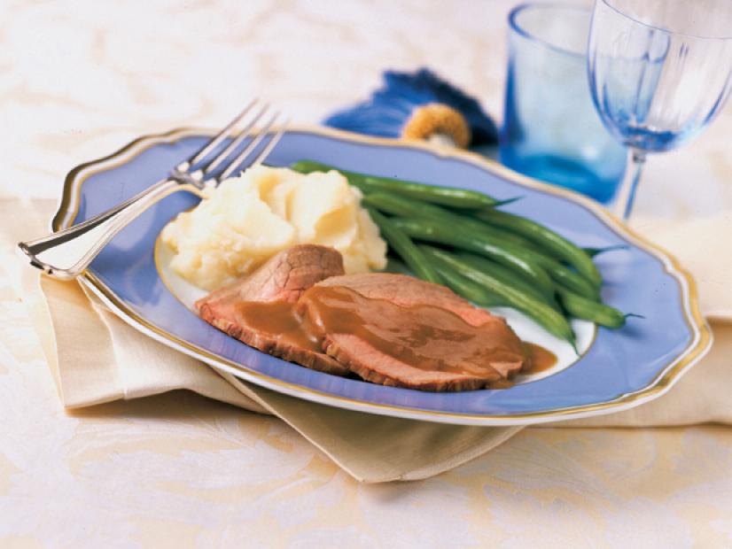 Slices of Roast Beef, Mashed Potatoes and Green Bean on a blue plate trimmed in gold