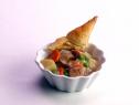 Chicken pot pie is served in a scalloped white bowl and a piece of bread on top.