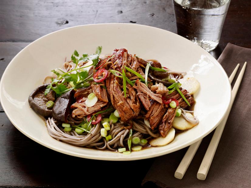 Asian Pork with Noodles in a White Dish on a Dark Wooden Table