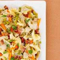 Noodles with Mixed Vegetables in a White Dish on an Orange Tablecloth