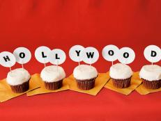 Five cupcakes with small letters on toothpics sticking out that spell Hollywood