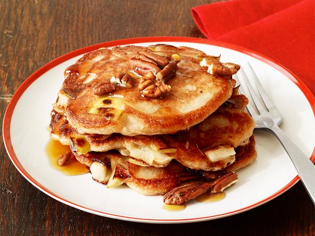 A stack of pancakes topped with syrup and walnuts