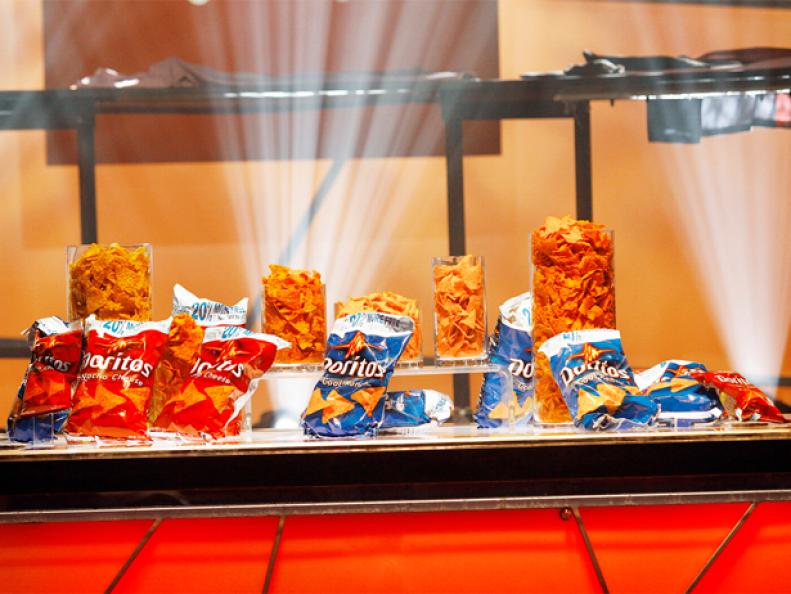 A table with bags of Doritos and glasses full of drinks from the Iron Chef competition