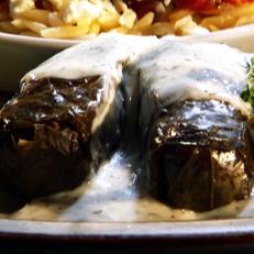 Salmon wrapped in grape leaves and covered in white sauce