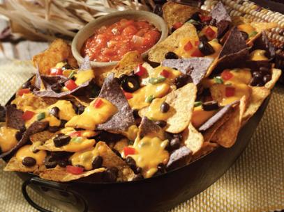 Deluxe Nachos made of two different tortillas with a side of salsa in a black pan