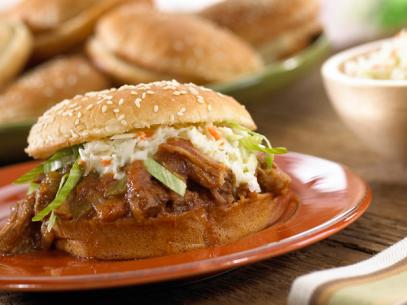 A pulled pork sandwich topped with coleslaw on a small red dish