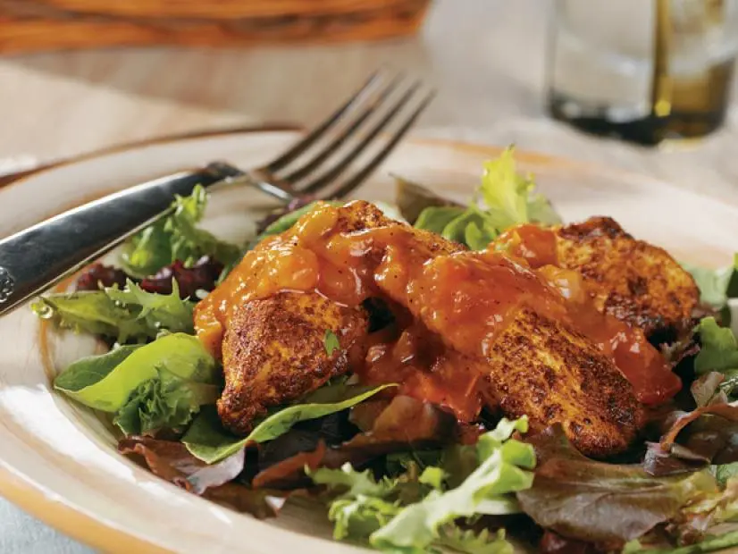 Chicken covered in salsa on a bed of salad