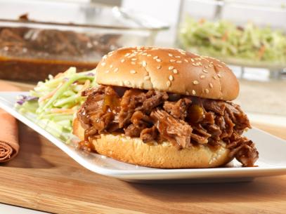 Sweet and Spicy Barbecue Brisket on a bun next to coleslaw on a white plate