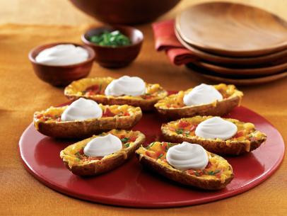 Six loaded potato skins placed on a small red platter with a dollop of Daisy Sour Cream on each one