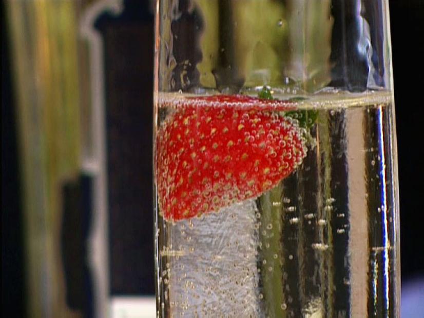 A Champagne glass containing Champagne and a single strawberry