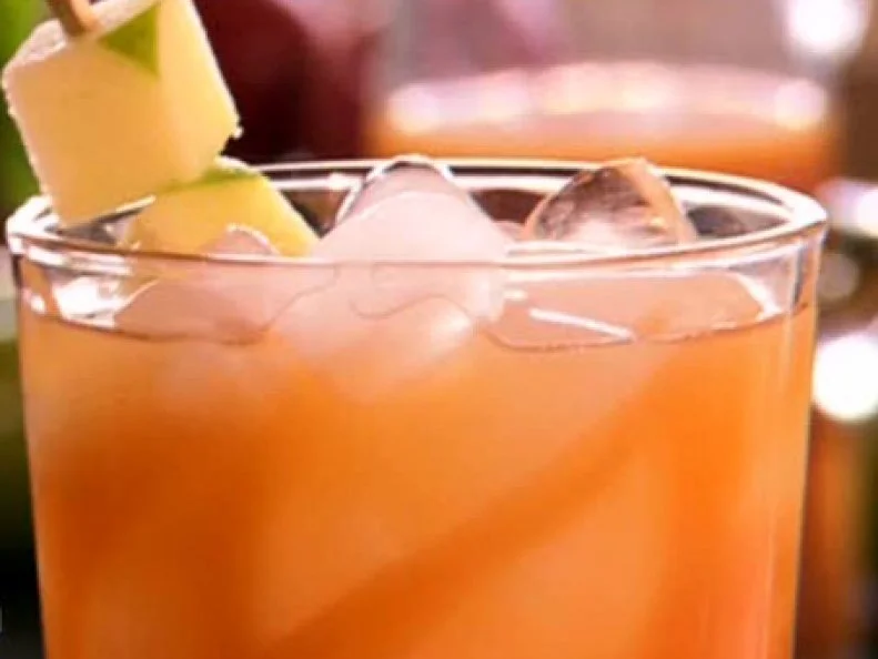 Spiked apple cider cocktail with a garnish of apple cubes on a stick.