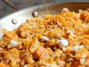 Candied sweet potatoes wit crunchy topping are cooked on the stove top.