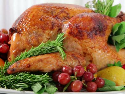 Herb and pear glazed turkey is garnished with grapes, pear, rosemary, and other herbs.