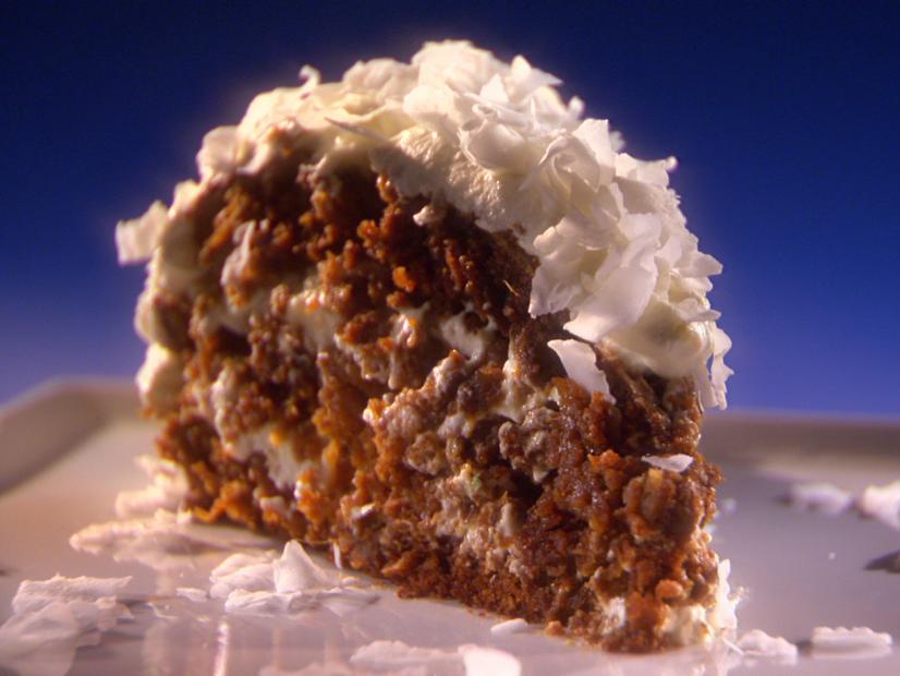 A slice of Marscapone Cake topped with coconut flakes placed on a thin gray square plate