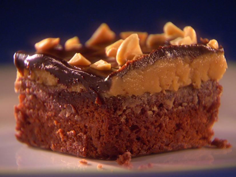 A Peanut Butter Brownie topped with chopped nuts on a small white plate