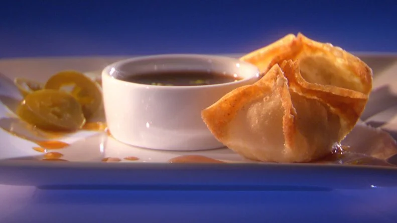 Two Texan Won Tons, sauce and slices of jajapeno on a square white plate