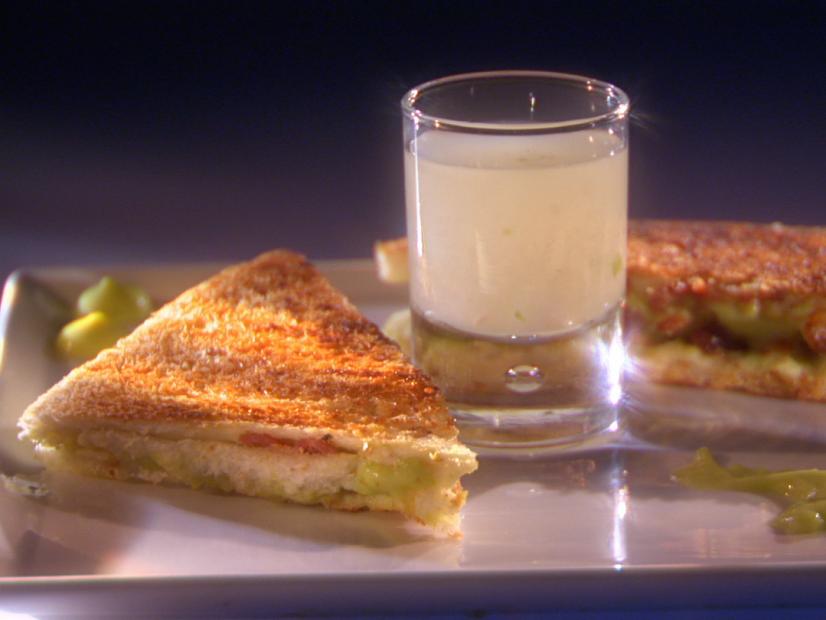 A grilled crustless sandwich halved on a plate place with a glass of juice