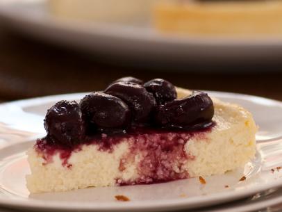A slice of Cherry Ricotta Cheesecake on a small stack of white dishes