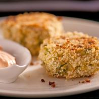 Two Crab Cakes along side a dish of spicy cream on a white plate