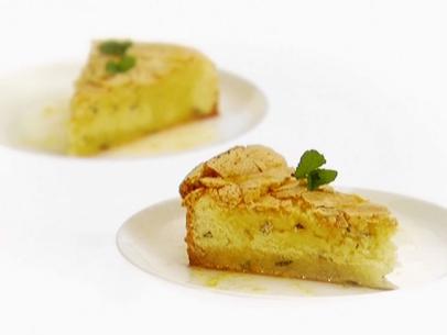 Two seperate slices of Lemon Mint Cake garnished with mint on plain white plates