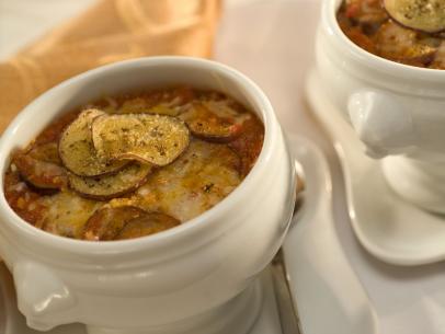 A soup made of shaved eggplant and parmesan in a white decorative bowl