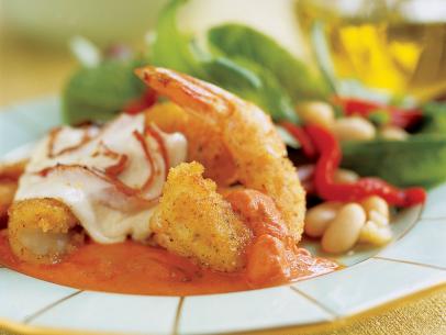 Shrimp in a pool tomato sauce and topped with cheese beside a bean salad