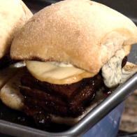 Braised pork belly sandwich is served on a ciabatta roll with pesto mayo and smoked mozzarella.