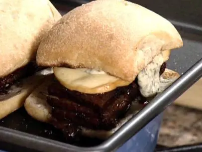Braised pork belly sandwich is served on a ciabatta roll with pesto mayo and smoked mozzarella.